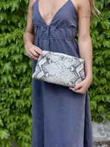 Mini bag tipo sobre con estampado de piel de serpiente en tonos blanco y negro, con cierre metálico plateado.
