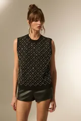 Chaleco negro sin mangas, con cuello redondo y diseño de rombos formados por strass.