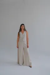 Conjunto de chaleco y pantalón de lino color beige. El chaleco es entallado con cuello en V y abotonadura frontal. El pantalón es de corte palazzo con cintura alta.