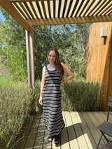 Vestido largo de punto a rayas horizontales negras y blancas, sin mangas, con cuello redondo y volados blancos en cuello y sisas.