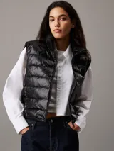 Chaleco puffer negro Calvin Klein Essentials, con cuello alto, cierre de cremallera, bolsillos laterales y logo estampado en el pecho.