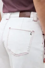 Pantalón de jean blanco crudo de tiro alto, corte culotte ancho y largo, con costuras en color rojizo.