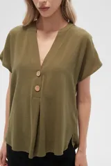 Blusa color crudo de viscosa, corte holgado, con cuello en v y cierre frontal con dos botones de madera.