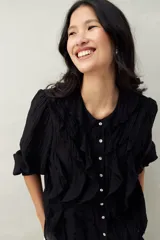 Camisa negra de tencel liviana con volados románticos y manga corta.