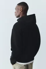 Campera con capucha H&M de felpa negra con interior cepillado suave. Tiene cierre frontal, bolsillos delanteros, puños y bajo en punto acanalado. Corte holgado.