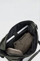 Bolso tote color verde oliva con detalles en negro. Tiene correa de hombro ajustable y extraíble, doble asa de mano, un compartimento principal con cierre, un bolsillo lateral externo, un compartimento interno para laptop de hasta 16 pulgadas y un bolsillo interno con cierre.
