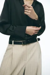 Camisa marrón satinada de cuello solapa, escote pico, manga larga y cierre frontal con botones.