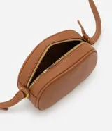 Bolso camera bag pequeño de poliuretano color negro, con forma redondeada, correa ajustable, bolsillo delantero y cierre superior.