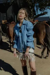 Camisa celeste de jean fino, con cuello clásico, cierre frontal con botones y mangas largas abullonadas con puños elastizados.