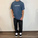 Remera azul con efecto gastado, corte holgado y estampado en el frente y la espalda con motivos surferos y el texto "Surf n' Destroy".