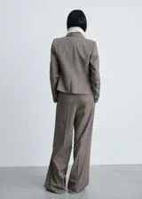 Pantalón de vestir color gris topo, de corte wide leg, tiro alto, con trabillas, cierre frontal con botón, gancho y cremallera, detalle de pinzas y dos bolsillos laterales.