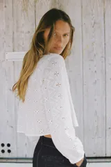 Camisa corta blanca con bordados perforados, cuello solapa, escote pico y manga larga abullonada.
