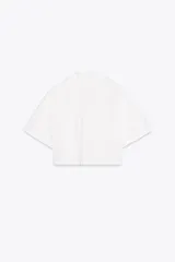Camisa celeste de popelín con cuello solapa, escote pico y manga corta. Presenta dos bolsillos delanteros de parche y cierre frontal con botones.