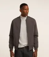 Campera bomber de poliéster color gris oscuro, con cuello alto, cierre frontal con cremallera, bolsillos laterales, mangas largas con puños ajustados y bajo con ajuste elástico.