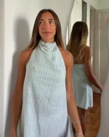 Vestido corto lila con cuello halter y espalda descubierta.