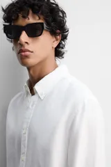 Camisa color arena de lino con cuello abotonado, manga larga con puños abotonados, corte regular y bajo con aberturas laterales.