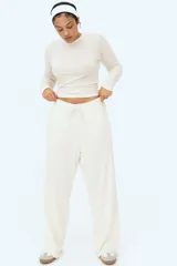 Pantalón deportivo de algodón color crudo, corte holgado, cintura elástica con cordón ajustable, bolsillos laterales y bajos sin rematar.