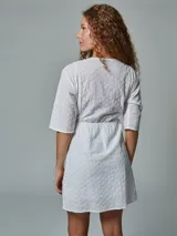 Vestido corto blanco con bordado broderie, escote en V y mangas cortas.