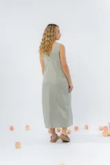 Vestido midi de lino en color verde seco, con escote en V, diseño sin mangas y cierre frontal con botones de madera. Presenta un corte recto y fluido con una abertura frontal en el bajo.