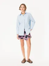 Camisa de poplin rayada rosa y celeste, de corte holgado, con cuello clásico, cierre frontal con botones y bolsillo plaqué en el pecho.