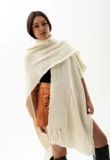 Ruana color crudo de tejido de punto grueso con flecos.