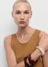 Vestido largo de tejido de punto fino color camel, sin mangas y con cuello redondo. Presenta un corte evasé que se ajusta al cuerpo en la parte superior y cae con vuelo en la falda.