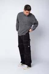 Pantalón cargo negro de corte relaxed fit y tiro medio, con múltiples bolsillos y costuras a contraste en color blanco.