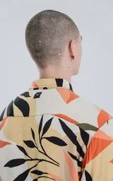 Camisa de manga larga con estampado de hojas en tonos beige, naranja, negro y verde.