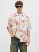 Camisa de manga corta con cuello resort y fit amplio, confeccionada en tejido plano de lino y algodón. Presenta un estampado de mosaicos en tonos rojo, naranja, azul y blanco.