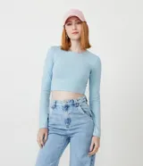 Blusa cropped celeste de algodón con cuello redondo y mangas largas.