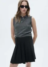 Minifalda negra con diseño evasé, de tablas y estampado de raya diplomática. Cierre de cremallera invisible en la parte posterior.