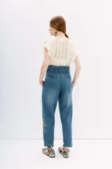 Pantalón de jean tiro alto con corte paper bag, lazo a tono en la cintura y bordado con lentejuelas y piedras en el lateral.