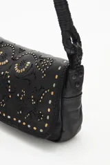 Cartera bandolera de cuero vacuno color negro, con correa trenzada y solapa con diseño calado y tachas. Incluye pañuelo estampado atado al asa.