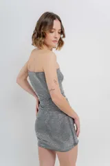 Minifalda negra ajustada al cuerpo, confeccionada en tejido elástico con strass plateado.