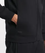 Saco deportivo gris de algodón y poliéster, con capucha ajustable con cordón, cierre frontal con cremallera, mangas largas con puños ajustados y bolsillos laterales.