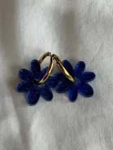 Par de aros colgantes con forma de flor azul brillante y aros dorados.