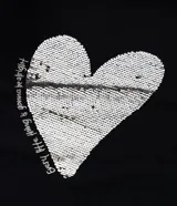 Remera negra de algodón con cuello redondo y manga corta. Presenta un estampado frontal de un corazón dorado de lentejuelas reversibles y texto blanco.