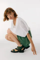 Sandalias de cuero marrón con tiras cruzadas y hebillas doradas.