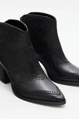 Botas negras de cuero vacuno con detalles de textura de piel de serpiente y tachas. Tienen punta fina y taco cuadrado.