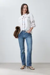 Camisa blanca con bordados florales en tonos rosa, azul y verde.