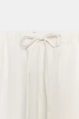 Pantalón jogger color gris claro, de tiro alto con cintura elástica ajustable con cordones, bolsillos delanteros y traseros con solapa, y puños elásticos en los tobillos.