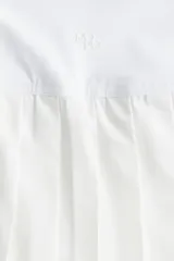 Minifalda deportiva blanca de tiro alto con cintura elástica y microshorts interiores con bolsillos laterales.
