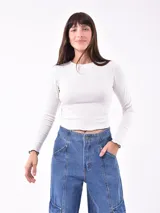 Remera blanca de manga larga con cuello redondo y estampado pequeño con la frase 'Busy ignoring someone' en el pecho.