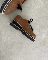 Zapato mocasín acordonado de cuero color marrón, con suela track negra y detalle de ribete color crema.