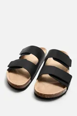 Sandalias negras con dos tiras anchas en el empeine con acabado engomado y ajustables mediante cierres adherentes. Plantilla con horma anatómica y suela de corcho.