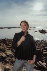 Blusa negra de lino con cuello mao, mangas largas y alforzas verticales en el frente.