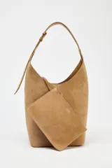Bolso tipo saca de cuero color marrón claro, con asa de hombro ajustable y cierre imantado. Incluye cartera interior con cierre de cremallera metálica.