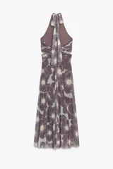 Vestido largo de tul con estampado floral en tonos marrón y celeste, cuello halter con lazada, escote pico cruzado, aberturas laterales en la cintura, frunces en la falda y forro interior.