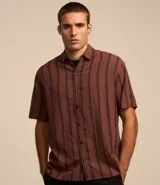 Camisa masculina de corte relajado, confeccionada en cáñamo, algodón y poliéster. Presenta cuello inglés, mangas cortas y rayas verticales texturizadas.