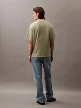 Remera color verde oliva de corte holgado, con cuello redondo, mangas cortas y bolsillo en el pecho con logo bordado.